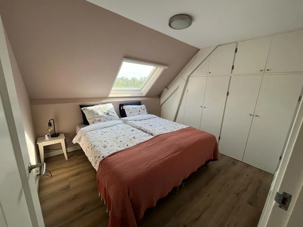 Slaapkamer met opgemaakt bed met bloemenlinnen en ruime kastenwand